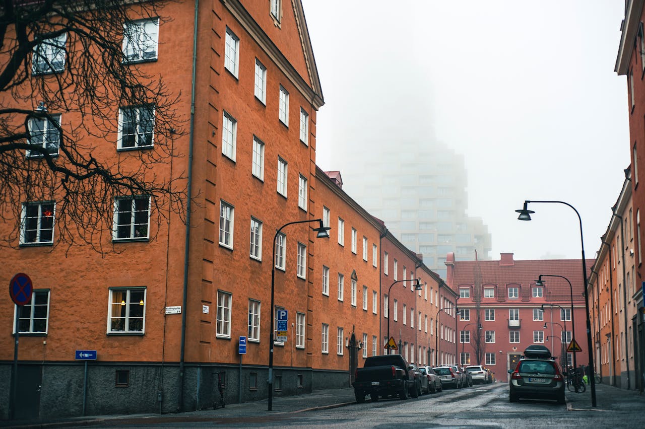 services-02 A foggy day on a residential street in Stockholm with parked cars and classic architecture.