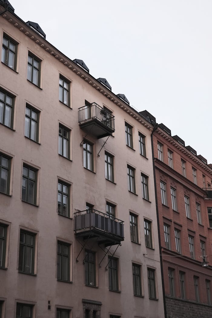 services-04 Elegant historic apartment facade in Stockholm with balconies and windows under a moody sky.